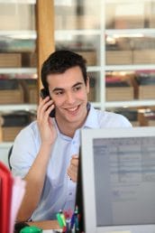 Male office worker speaking to customer on the telephone
